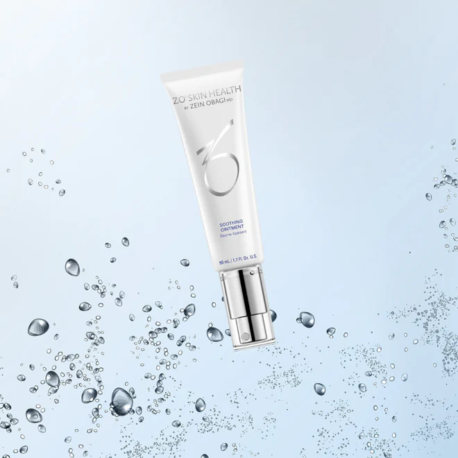 Un tube de pommade apaisante ZO Skin Health se dresse sur un fond bleu clair avec des gouttelettes d'eau, évoquant une sensation de fraîcheur et d'hydratation - disponible à la Clinique médico-esthétique Viva pour des solutions de soins de la peau avancées.